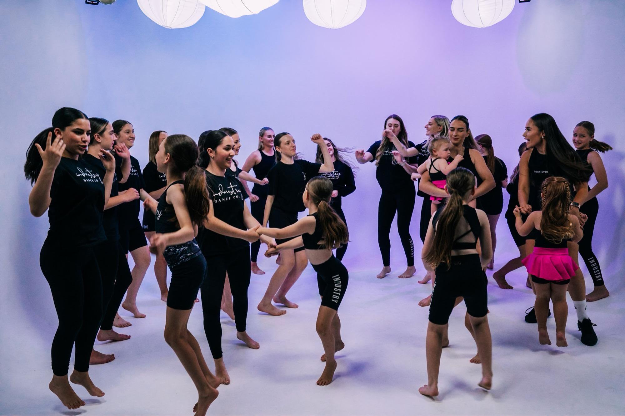 Dancers moving together under lilac studio light