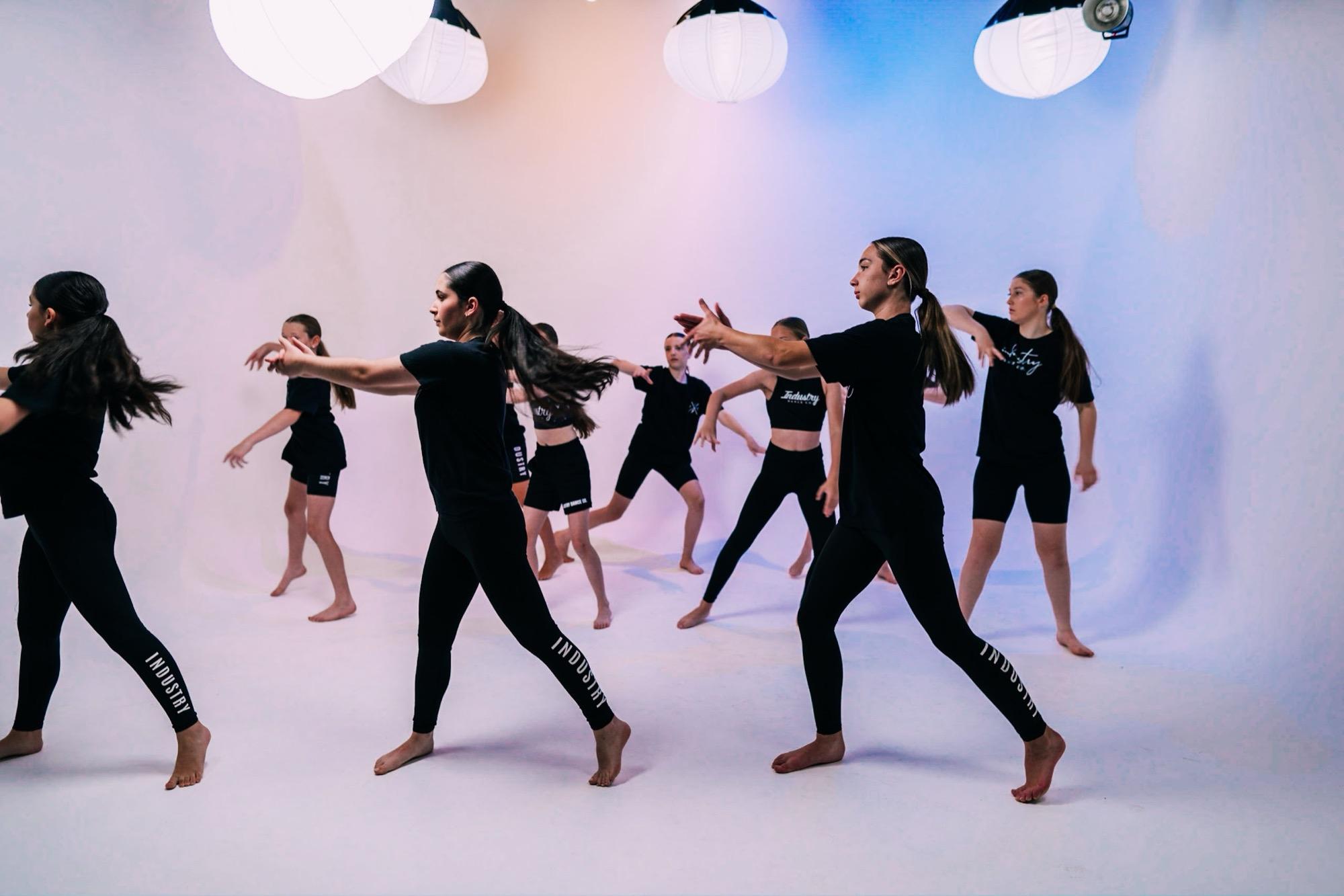 A class of dancers rehearsing in rows on the studio floor