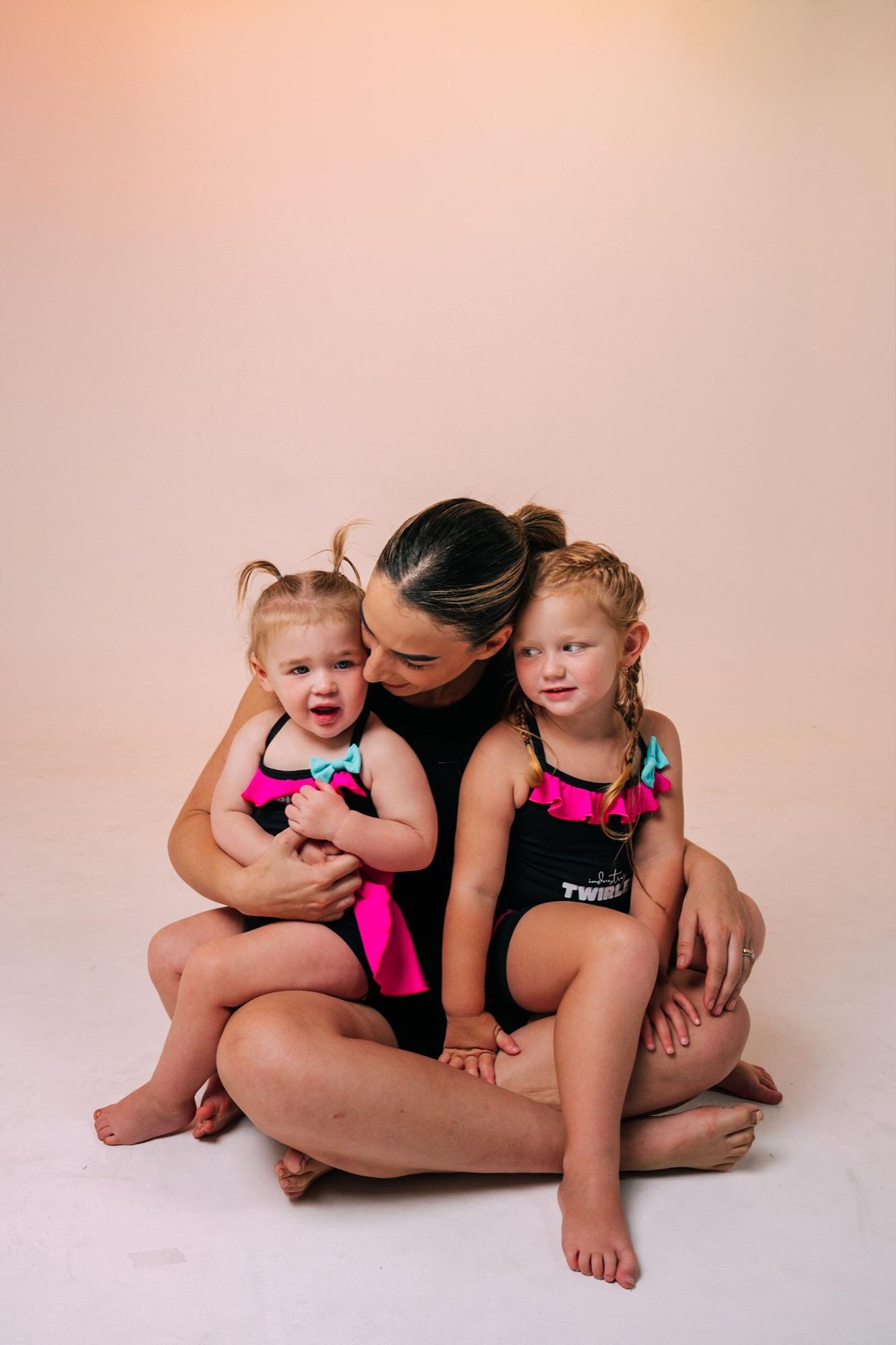 An IDC teacher cuddling two giggling Twirlers on the studio floor