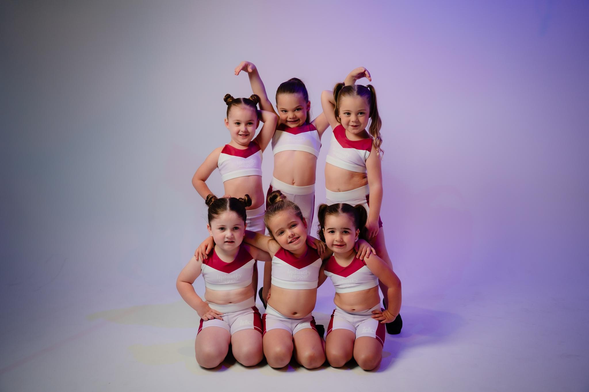 Six young dancers in matching costumes posing as a group